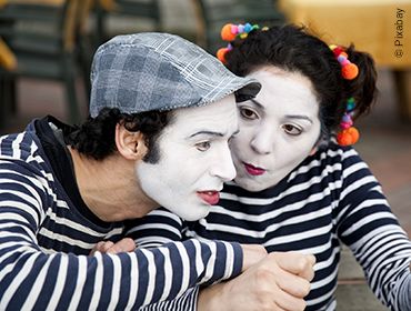 Zwei Personen in pantomimischer Darstellung. Der Mann sieht fragend nach vorne und die Frau blickt ihn gezielt mit einer Fischmund-&auml;hnlichen Mimik an.